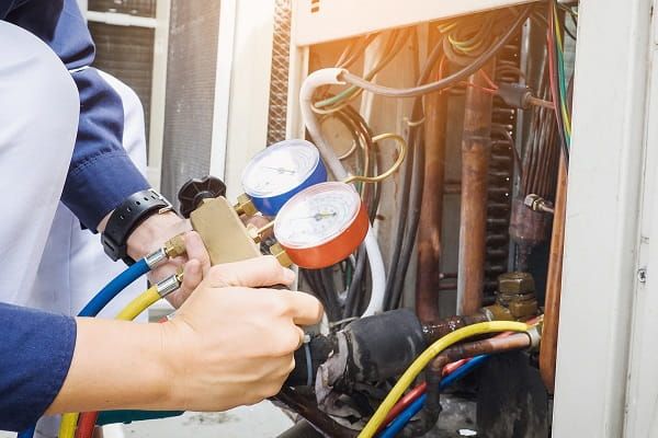 A technician checking air conditioning pressure gauges